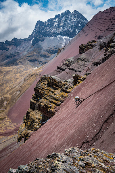 Mountain biker riding down dark red talus slope
