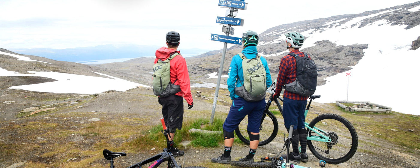 EVOC backpacks worn by mountain bikers looking at trail signs
