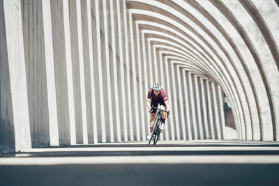 EVOC athlete sprinting on a road bike amongst shadow contrasting concrete architechture