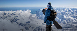EVOC winter protection backpack worn by snowboarder atop a snowy mountain