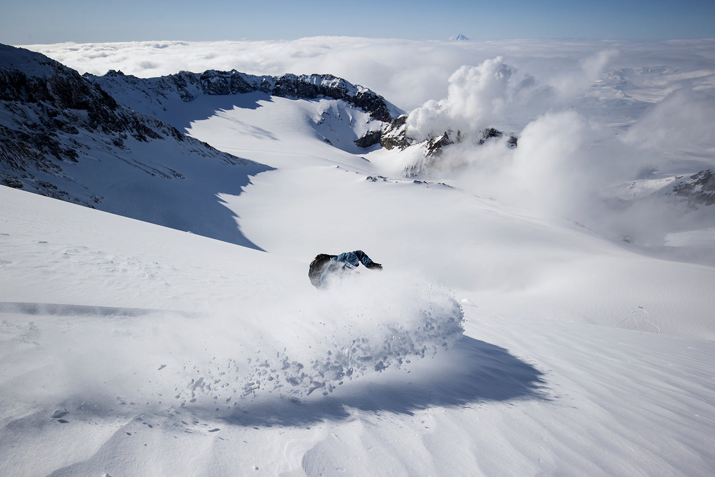 Snowboarder riding down fresh powder slope