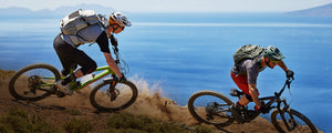Mountain bikers wearing EVOC backpacks while riding with sea in the background
