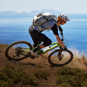 Mountain bikers wearing EVOC backpacks while riding with sea in the background mobile view