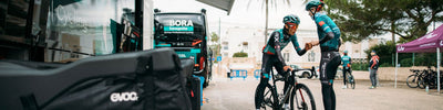 EVOC sponsored BORA hansgrohe professional riders greet each other at spring team training camp with EVOC Road Bike Bag Pro in foreground