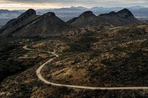 Group of bikepacking riders using EVOC bike bags on winding gravel road with mountains in the background