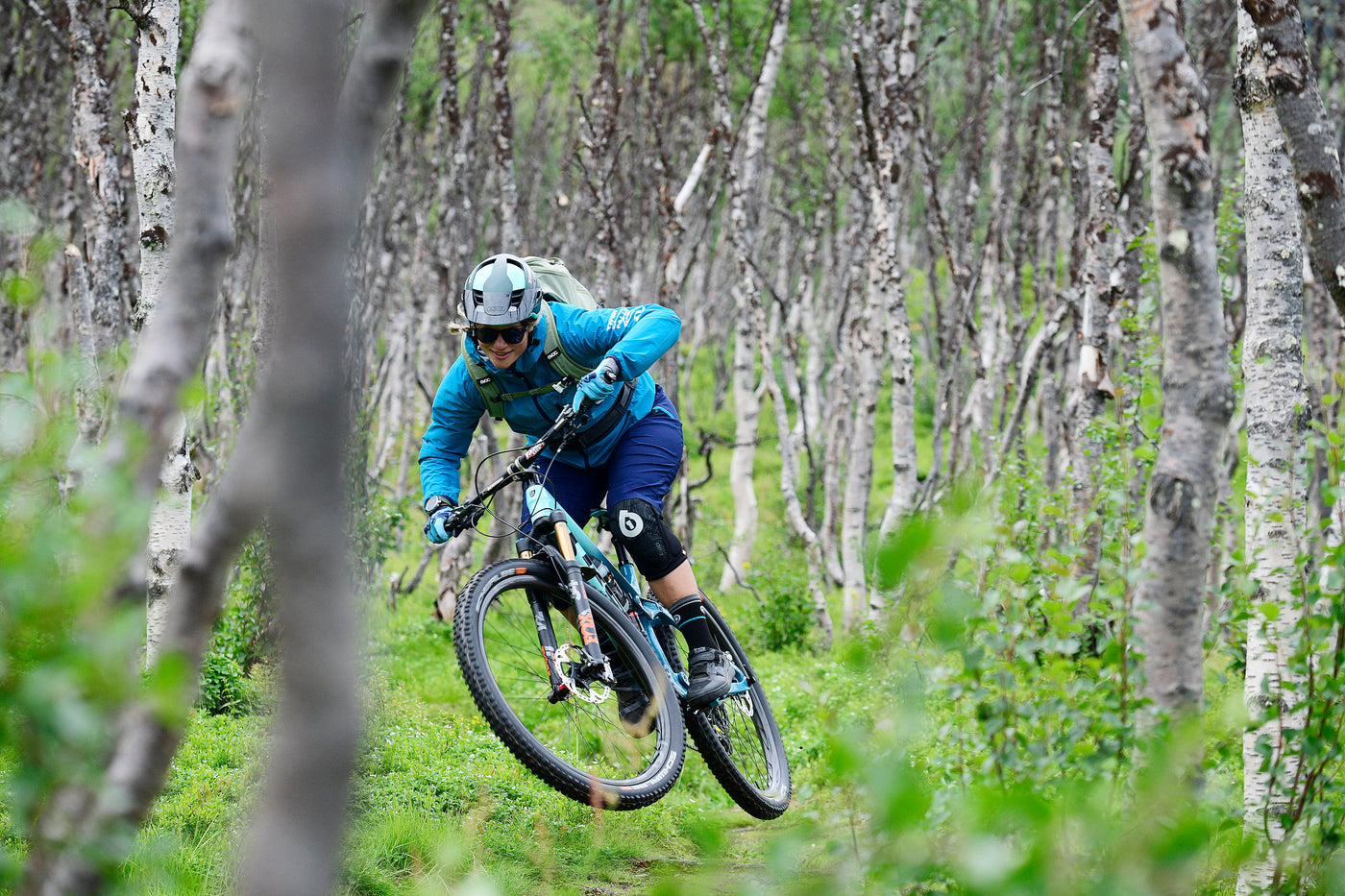 EVOC backpack worn by mountain biker in lush green forest