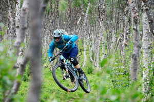 EVOC backpack worn by mountain biker in lush green forest
