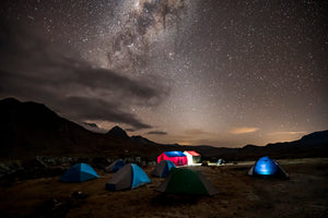Tents lit from inside on a starry night in the mountains