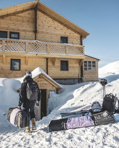 EVOC Snow Gear Roller, backpack and luggage outside a ski chalet
