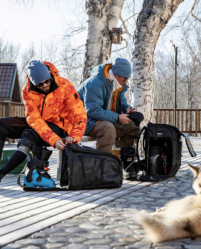 EVOC Gear Bags being used by two men changing into their ski & snowboard boots and other equipment